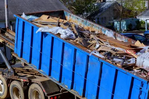 Blue Dumpster Filled With Construction Debris And Waste For Removal